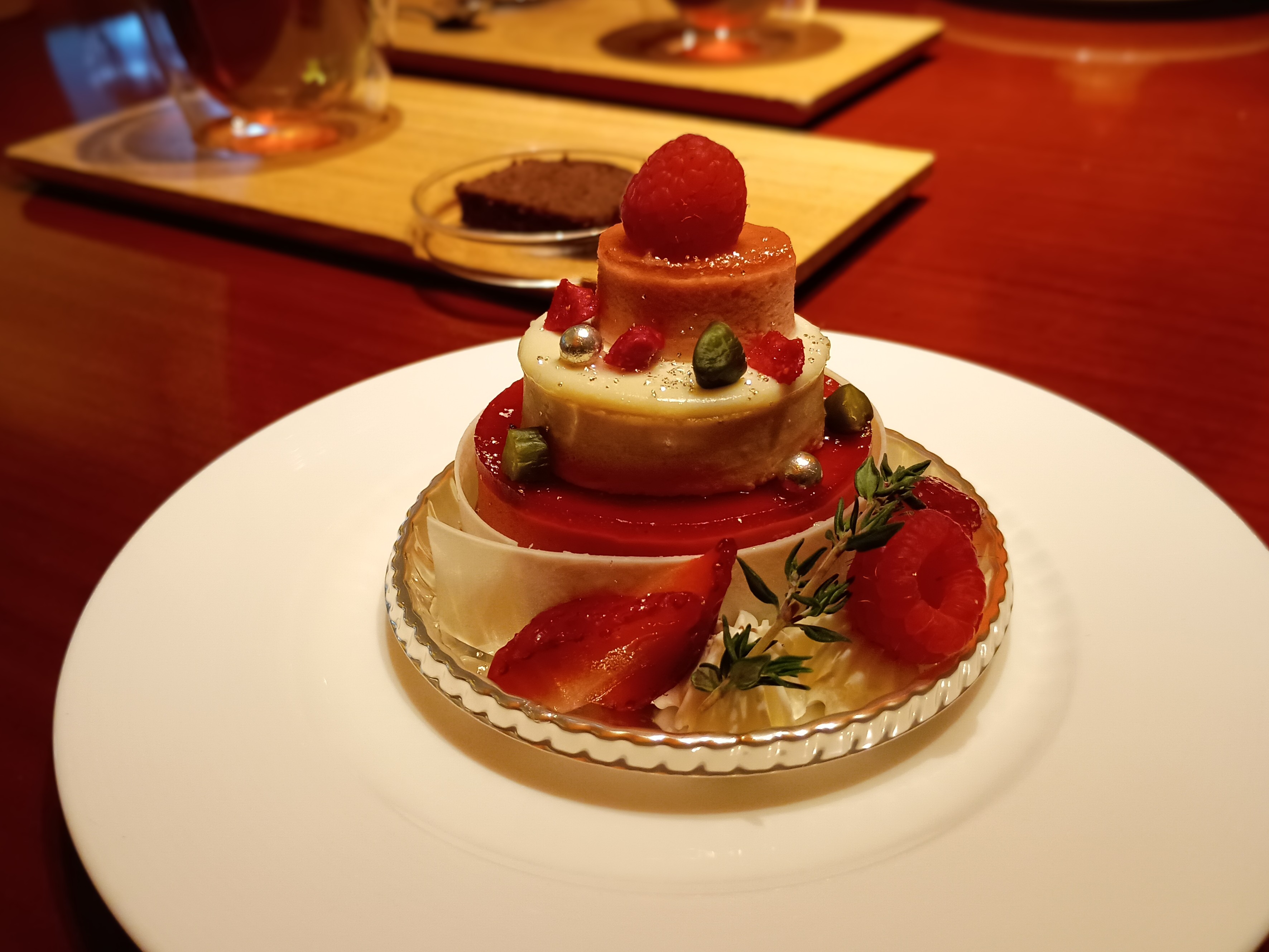 パティスリー ストレスの「ストロベリーとスパイスティーのケーキ」。3段重ねのウェディングケーキのような華やかなビジュアル。フランボワーズと苺のムースをホワイトチョコレートで包み、ピスタチオ・イチゴ・ラズベリーが飾られた繊細な一皿